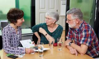 Eine Frau informiert ein älteres Paar über das Angebot und die Dienstleistungen im Berner Generationenhaus
