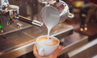 In der Cafébar des Berner Generationenhaus giesst jemensch aufgeschäumte Milch in eine Tasse Kaffee.