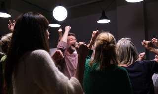 Gruppe die lachend die Hände in die Luft streckt.