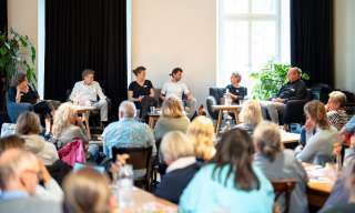 Auf der Bühne in der Cafébar des Berner Generationenhaus sitzen mehrere Menschen und diskutieren vor dem Publikum.