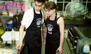 Junge Menschen stehen in einer Küche und backen Pizza.