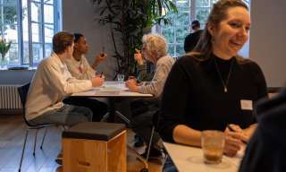 Personen diskutieren angeregt an Tischen.